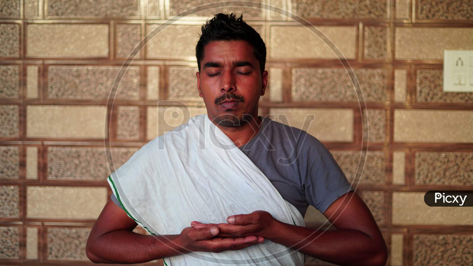 Young Indian Man Sitting In Yoga Position And Meditating At Home. Worldwide Yoga Day Concept.