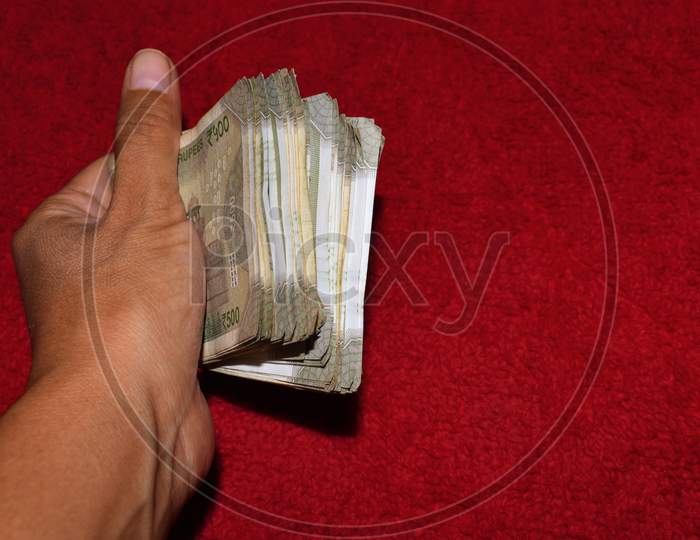 500 Indian Currency In Hand Red Background