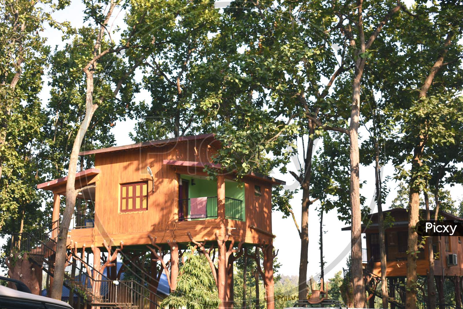 A Wooden Tree House Build In A Resort Surrounded By Green Trees