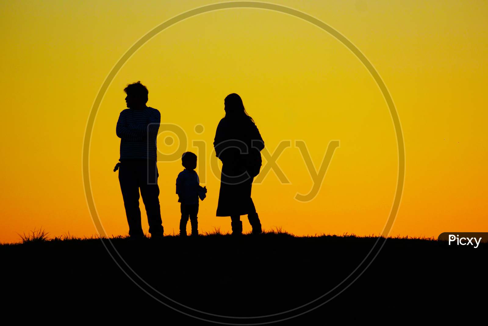 Family Standing On The Evening Of The Hill
