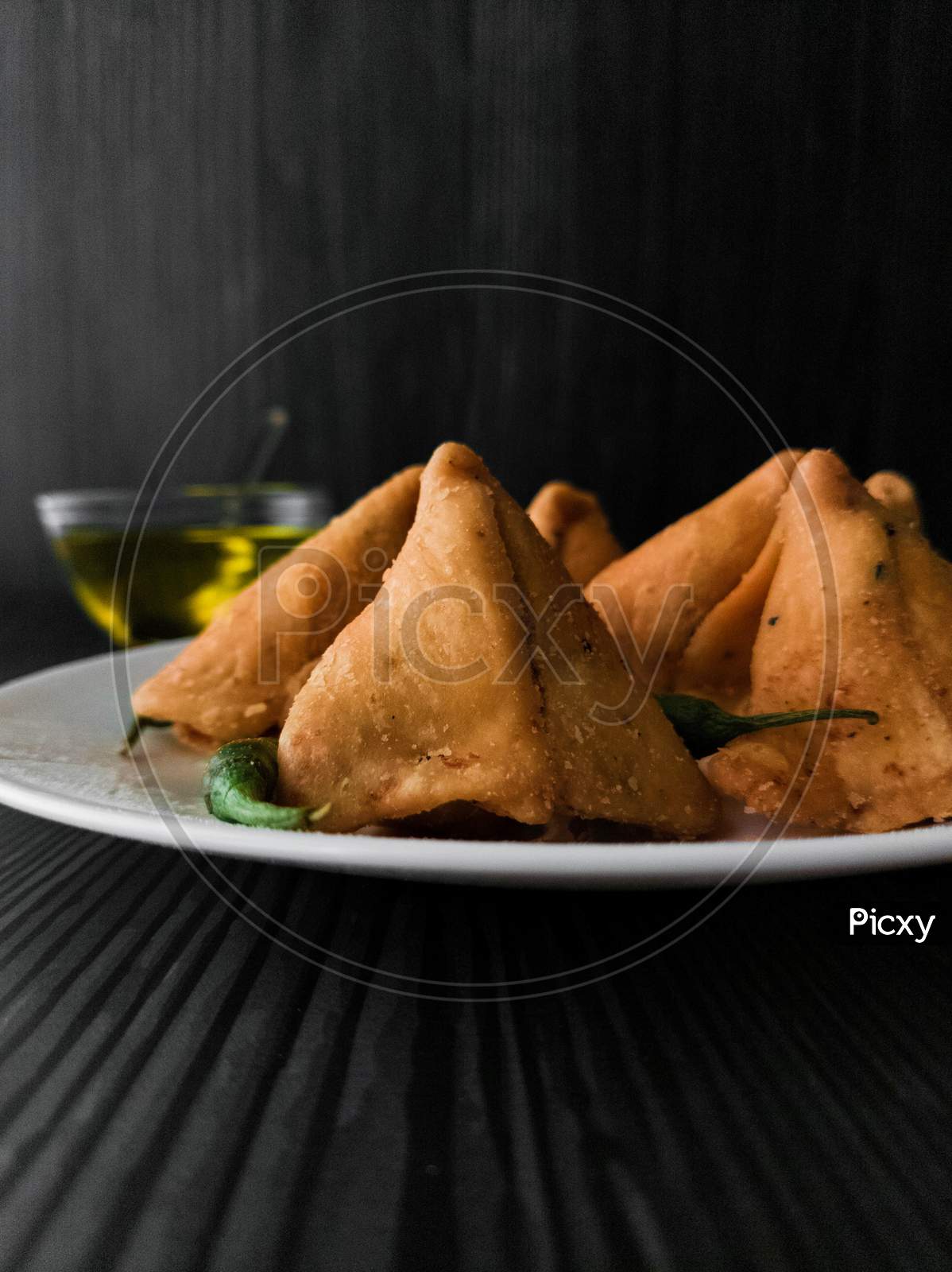 Samosa and green chilli served in a plate
