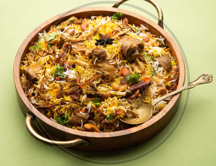 Indian Mutton Biryani Prepared In Basmati Rice Served With Yogurt Dip Over Moody Background, Selective Focus