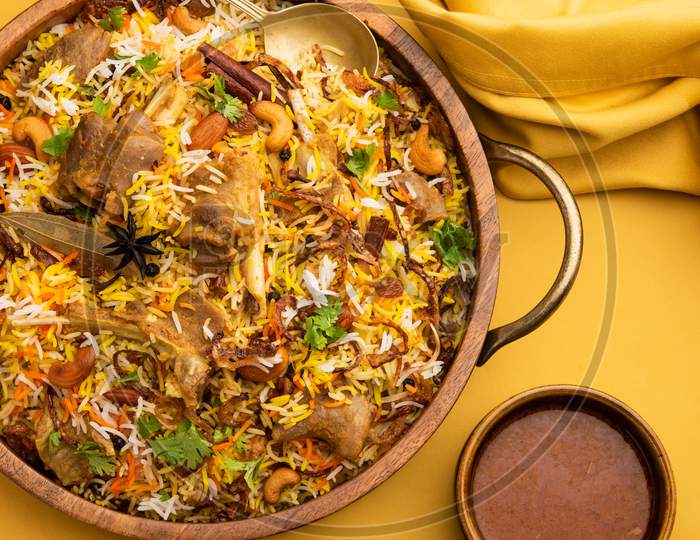 Indian Mutton Biryani Prepared In Basmati Rice Served With Yogurt Dip Over Moody Background, Selective Focus