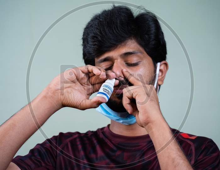 Young Man Inhaling Coronavirus Covid-19 Nasal Vaccine Spray To Nostril To Protect Fron Viral Infection