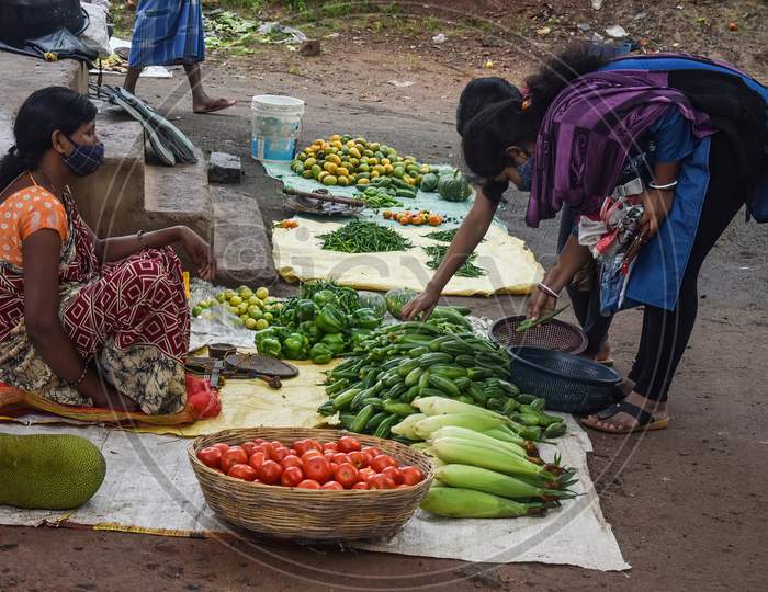 Poor road side vegetable sellers from India trying hard to sell their vegetables. Local street vendor selling vegetables. Assorted vegetables.