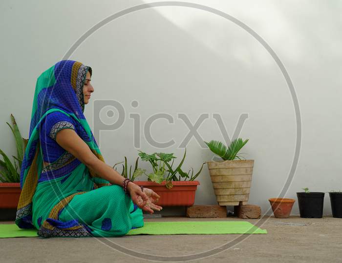 Jaipur, Rajasthan, India - June 21: A Pretty Looking House Wife Sitting In Open Doing Meditation Wearing Indian Traditional Sari.