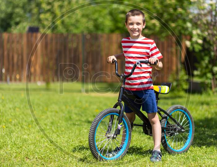 A Young Funny Boy Child Riding Bicycle Or Bike In The Summer