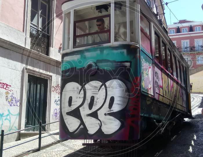 TRAM WITH GRAFFITI ON OLD COBBLESTONE STREET, PORTUGAL, LISBON