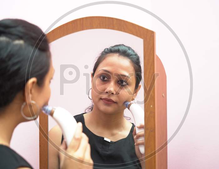 A Lady In 30S Using Vacuum Skin Sucker Cleaner In Front Of A Mirror As A Part Of Beauty Makeup