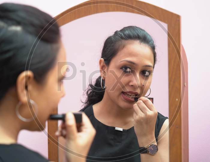 A Lady In 30S Putting Lipstick Make Up In Front Of A Mirror