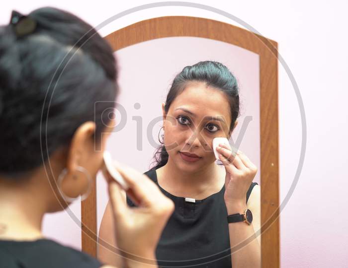 A Lady In 30S Putting Make Up In Front Of A Mirror