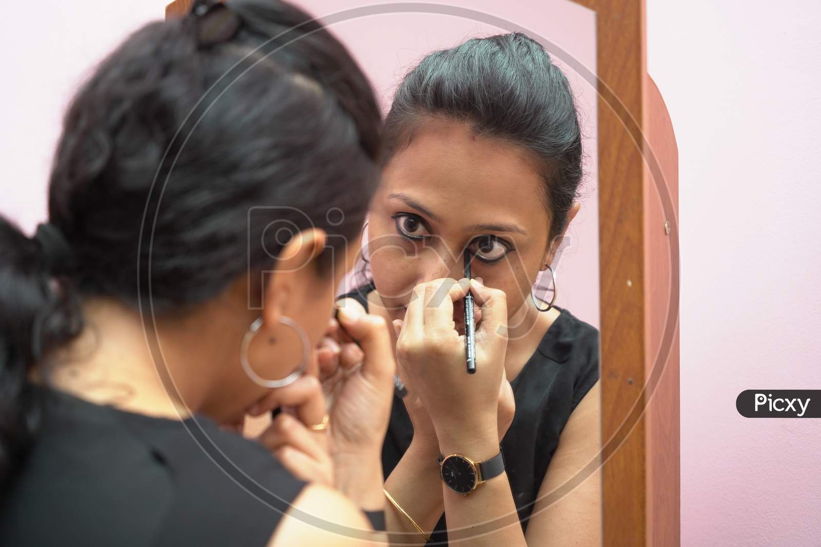 A Lady In 30S Putting Leye Liner Make Up In Front Of A Mirror. Close Up View
