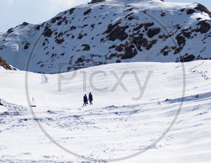 People Hiking On Mountain Top Covered By A Thick Layer Of Snow