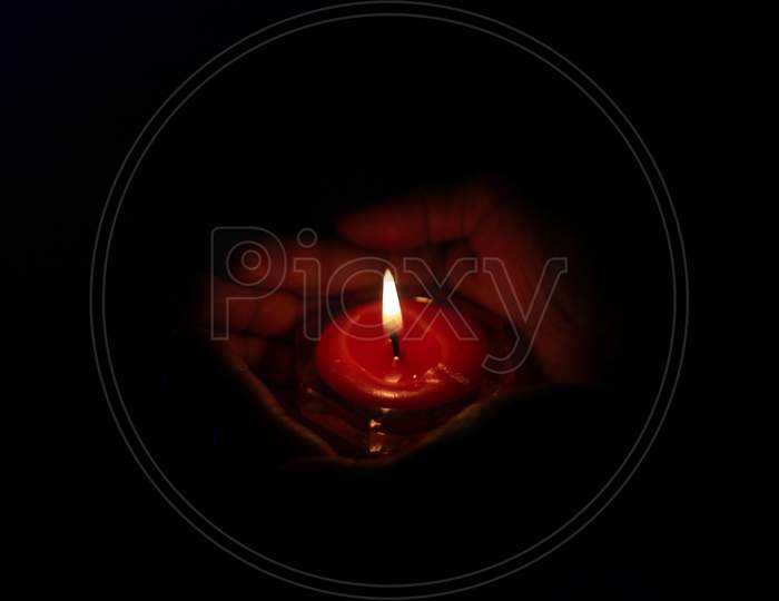 Burning candle in the hands of a girl. Christmas candles. Candle light glowing in woman's hands. Praying, faith, religion concept.