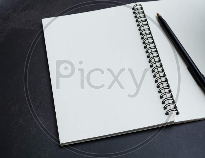 White Notebook And Pen On Dark Background. Space For Text