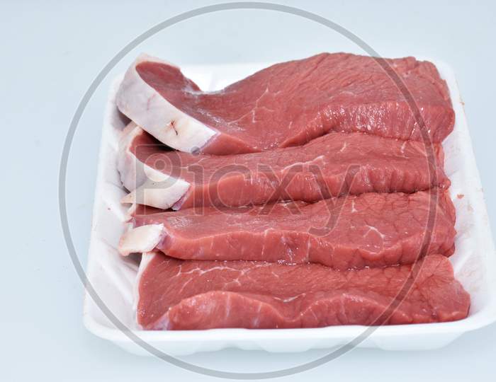 fresh boneless lamb meat sliced pieces decorated in plate on white background closeup,flank portion