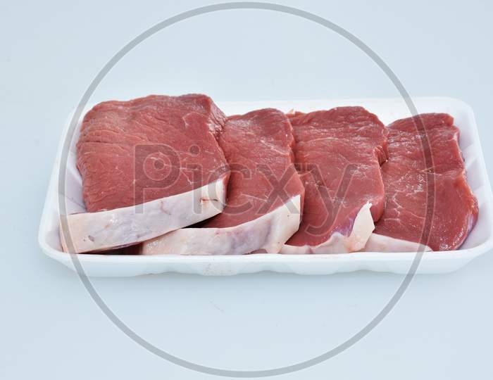 fresh boneless lamb meat sliced pieces decorated in plate on white background closeup,flank portion