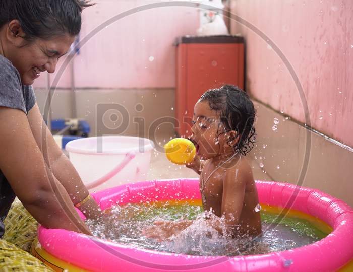 Indian Baby Boy Enjoying Bath In An Inflatable Pool With Mother