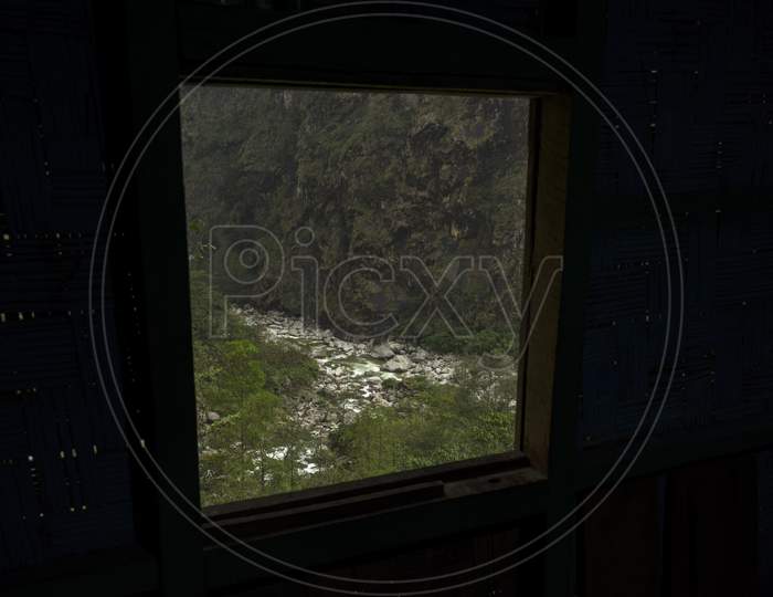 View Of Beautiful Landscape Of Water Fall With Mossy Green Rocks Of North Sikkim, India, Through A Small Window.