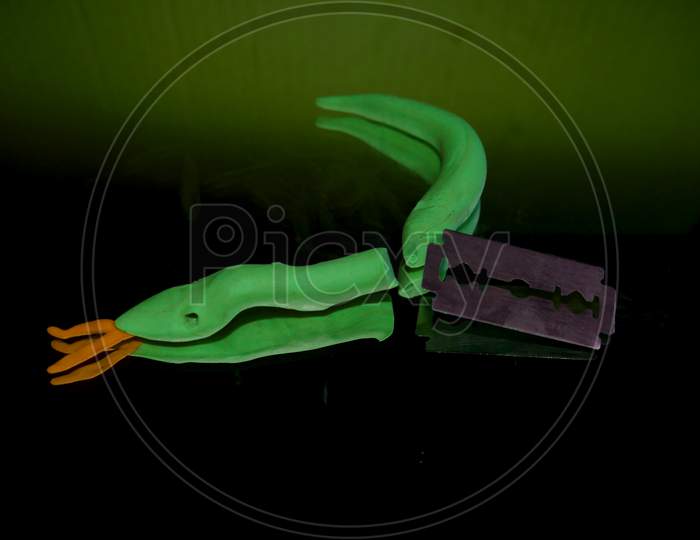 Clay Snake Cutting In Two Parts From Metal Blade, Animal Killing Concept.