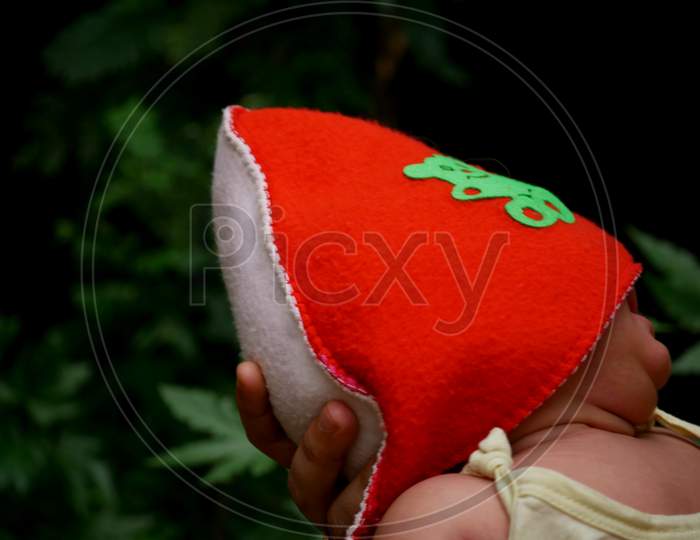 Cute Baby Wearing Red Color Cap Holding By Mother Hand On Nature Background.