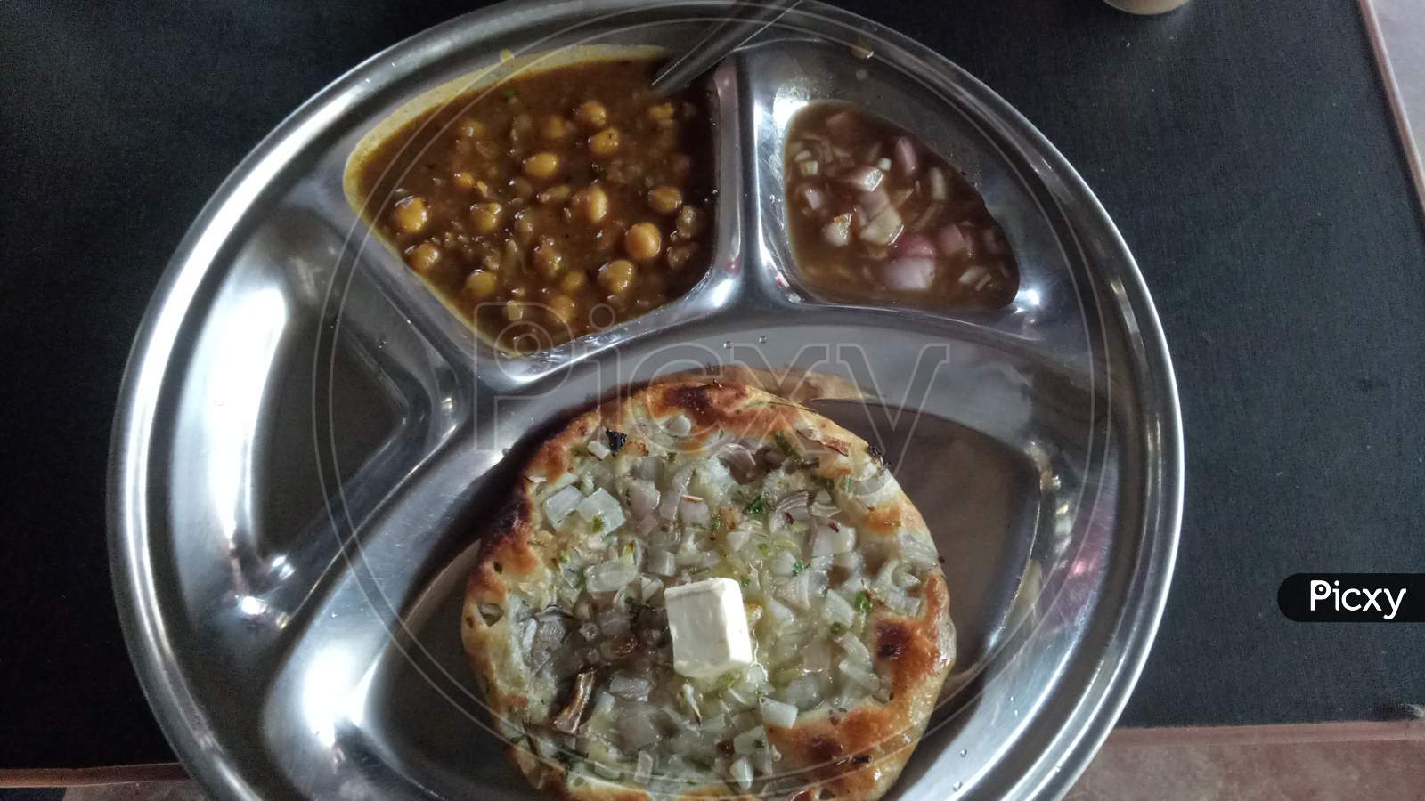 Image of Punjabi dish Chola kulcha or chickpeas curry with flour chapati served on steel plate