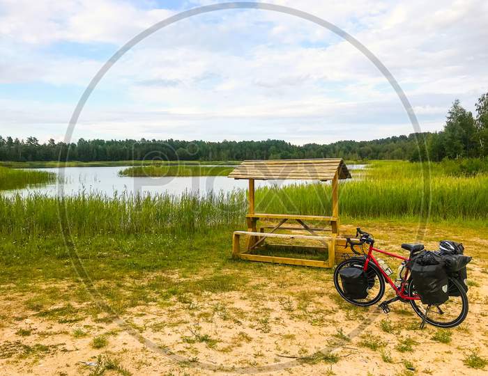 Fully Loaded Touring Bicycle Standing By Wooden Table With Lake Background.Bicycle Touring In Lithuania Countryside.