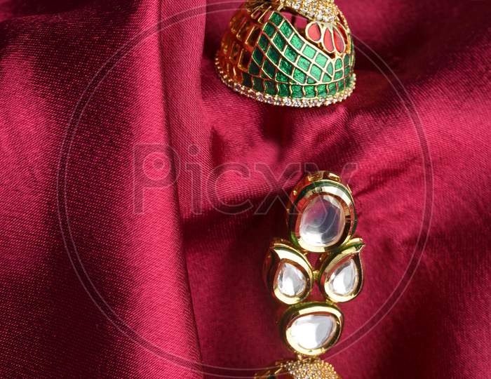 Beautiful Golden Pair Of Earrings Diamonds Gemstones On A Red Satin Background. Luxury Female Jewelry, Indian Traditional Jewellery, Kundan Earring,Bridal Gold Earrings Wedding Jewellery