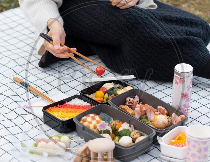 Woman having a picnic outdoors, barbecue grill with vegetables
