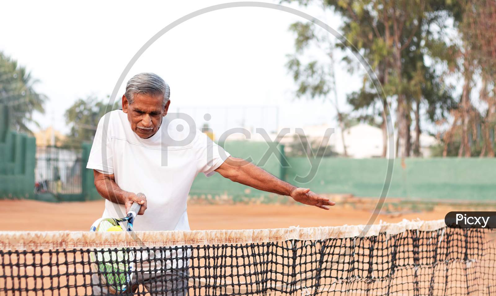Elderly Man Practicing Tennis Near Net - Concept Of Healthy And Fit Active Old People.