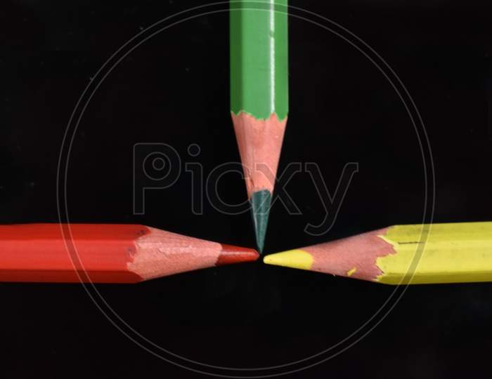 Red, green and yellow pencil on black background