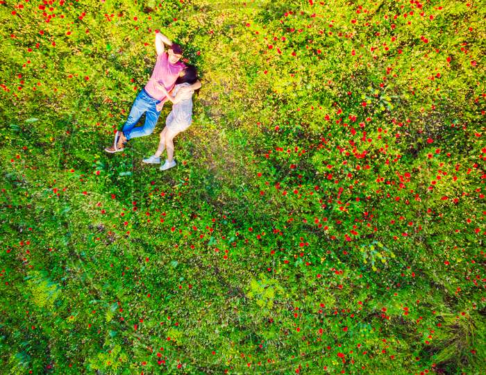 Top View Of Happy Couple Lying On The Grass In Summer Park.Couple In Love Spending Time Together Outdoors. Relationships Aerial Vertical Shot