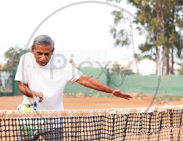 Elderly Man Practicing Tennis Near Net - Concept Of Healthy And Fit Active Old People.