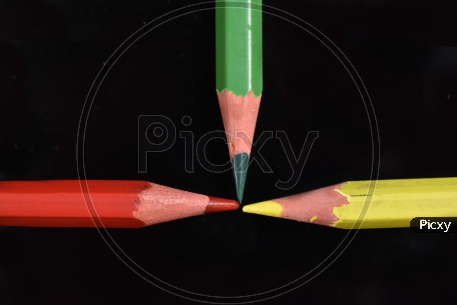 Red, green and yellow pencil on black background