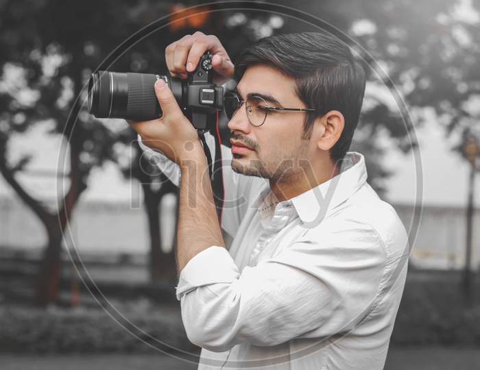 A Man in Black Pullover Standing while Holding a DSLR Camera · Free Stock  Photo