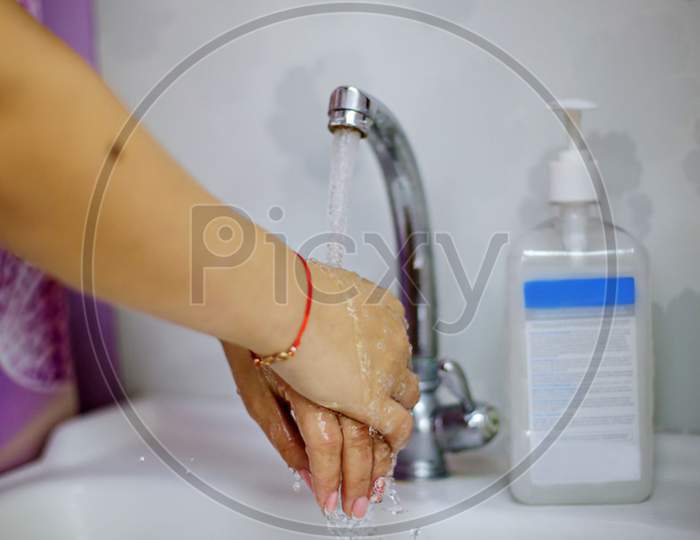 a woman washes her hands next to an alcohol gel or antibacterial disinfectant soap