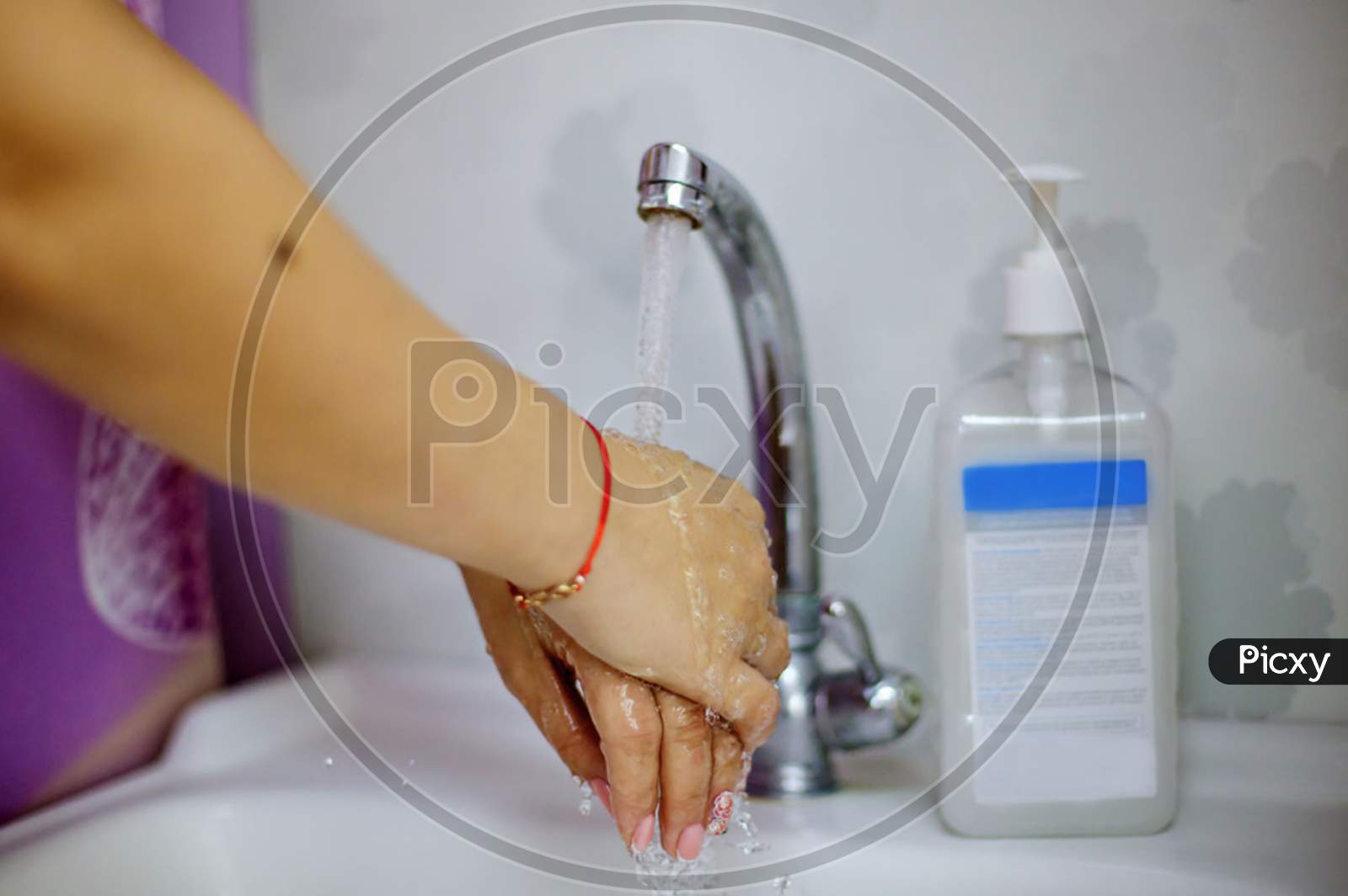 a woman washes her hands next to an alcohol gel or antibacterial disinfectant soap
