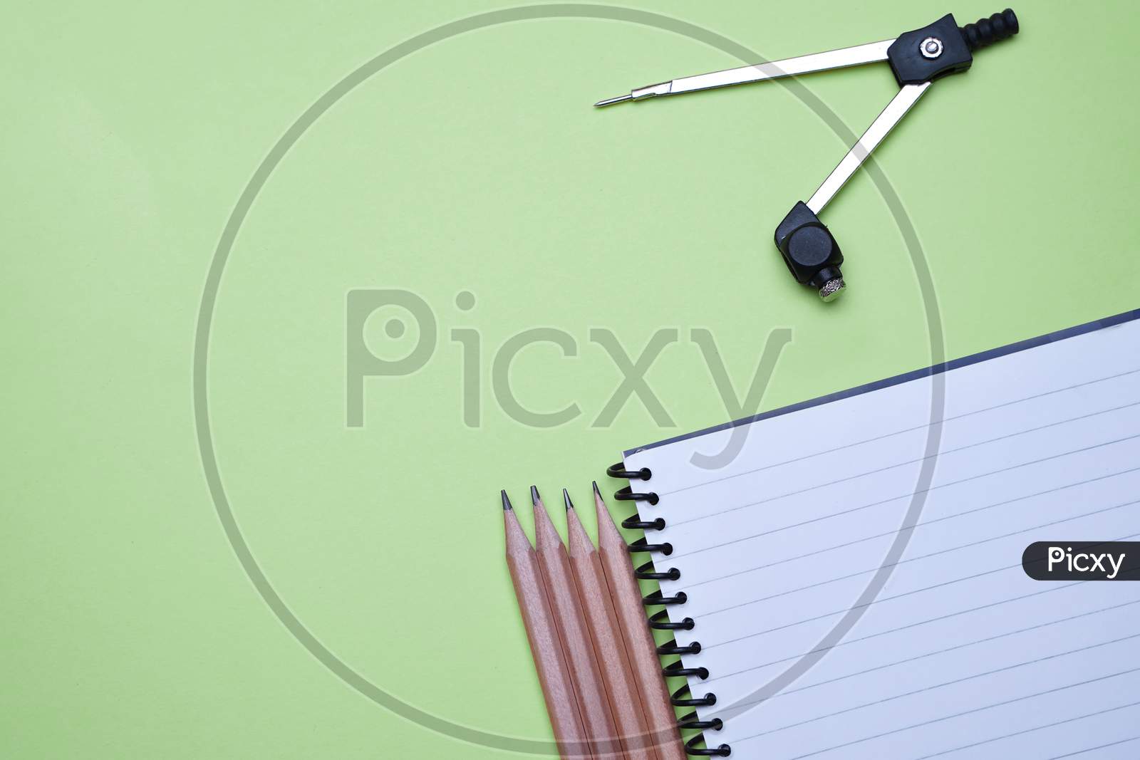 Business, Office, Student, Education Flat Lay, Table Top. Pencils, Compass, Spiral Notebook On Green Background