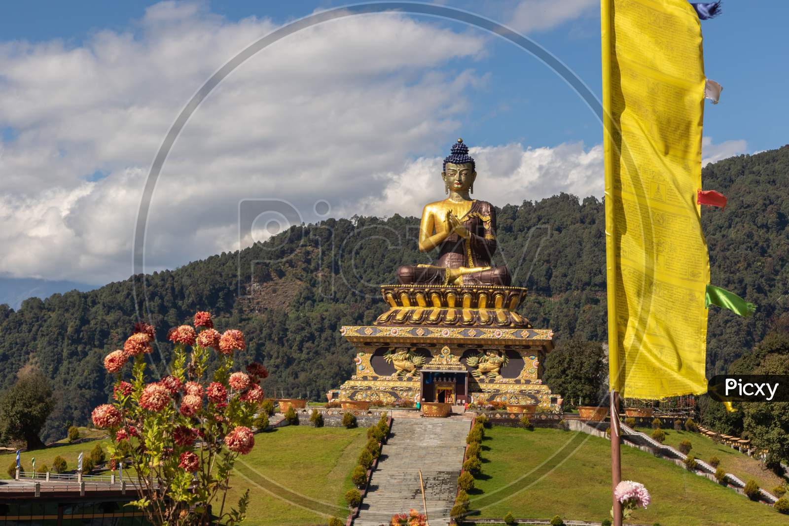 Buddha statue with clouds in the background and prayer flags in the foreground