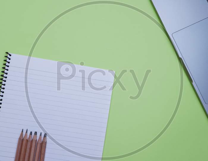 Office Top View For Corporate Use. Laptop, Pencils And A Notebook On A Green Background