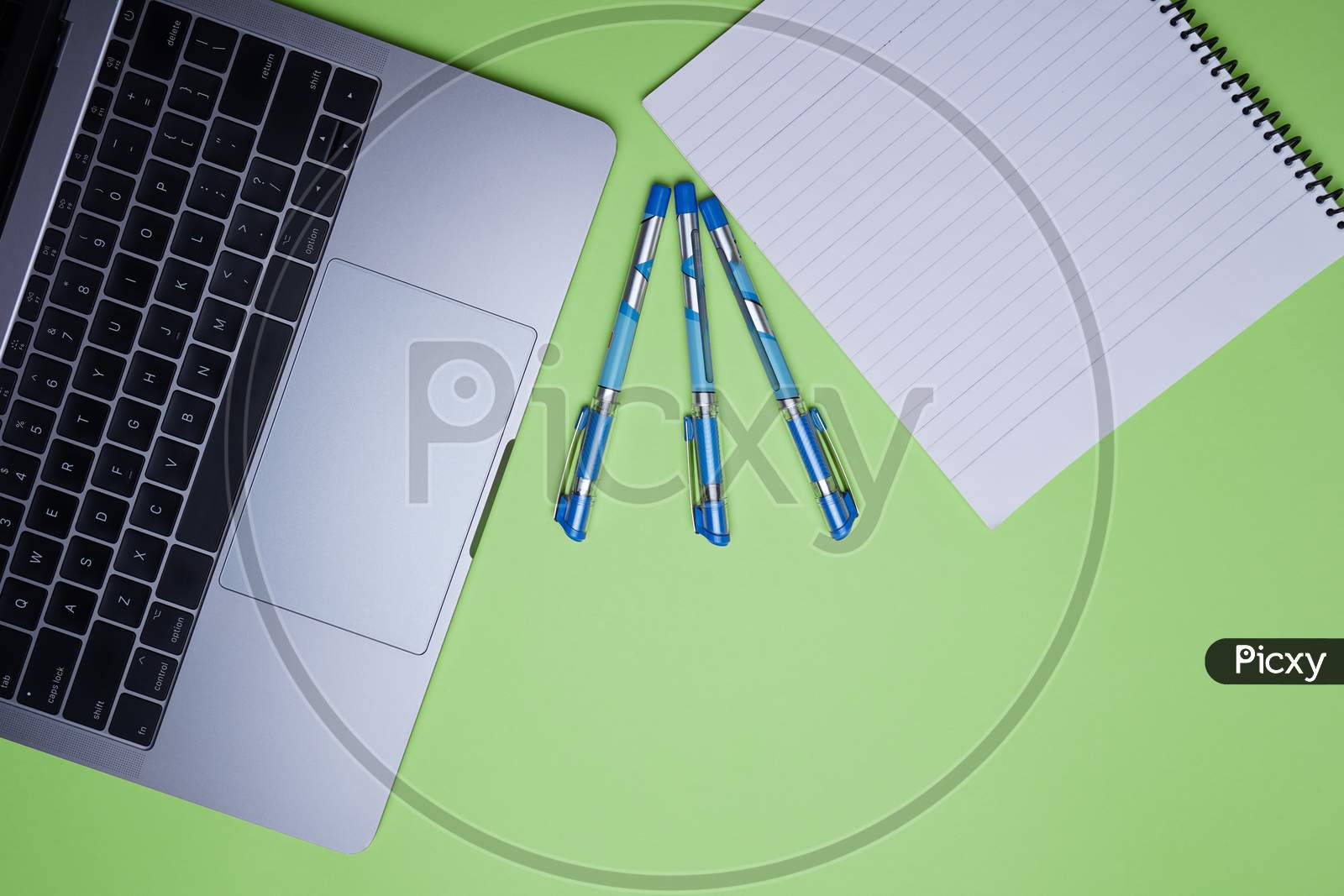 Creative Office, Business Professional Table Top, Flat Lay. Laptop, Pen And White Notebook On Green Background