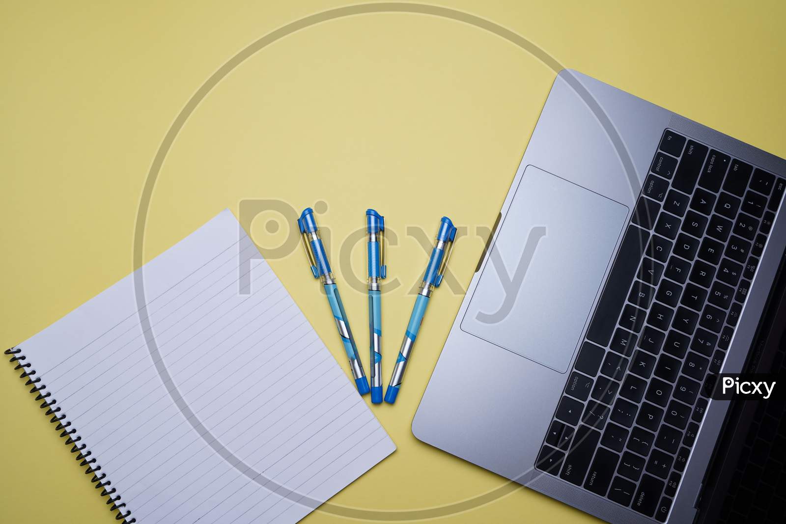 Creative Office, Business Professional Table Top, Flat Lay. Laptop, Pen And White Spiral Notebook On Yellow Background