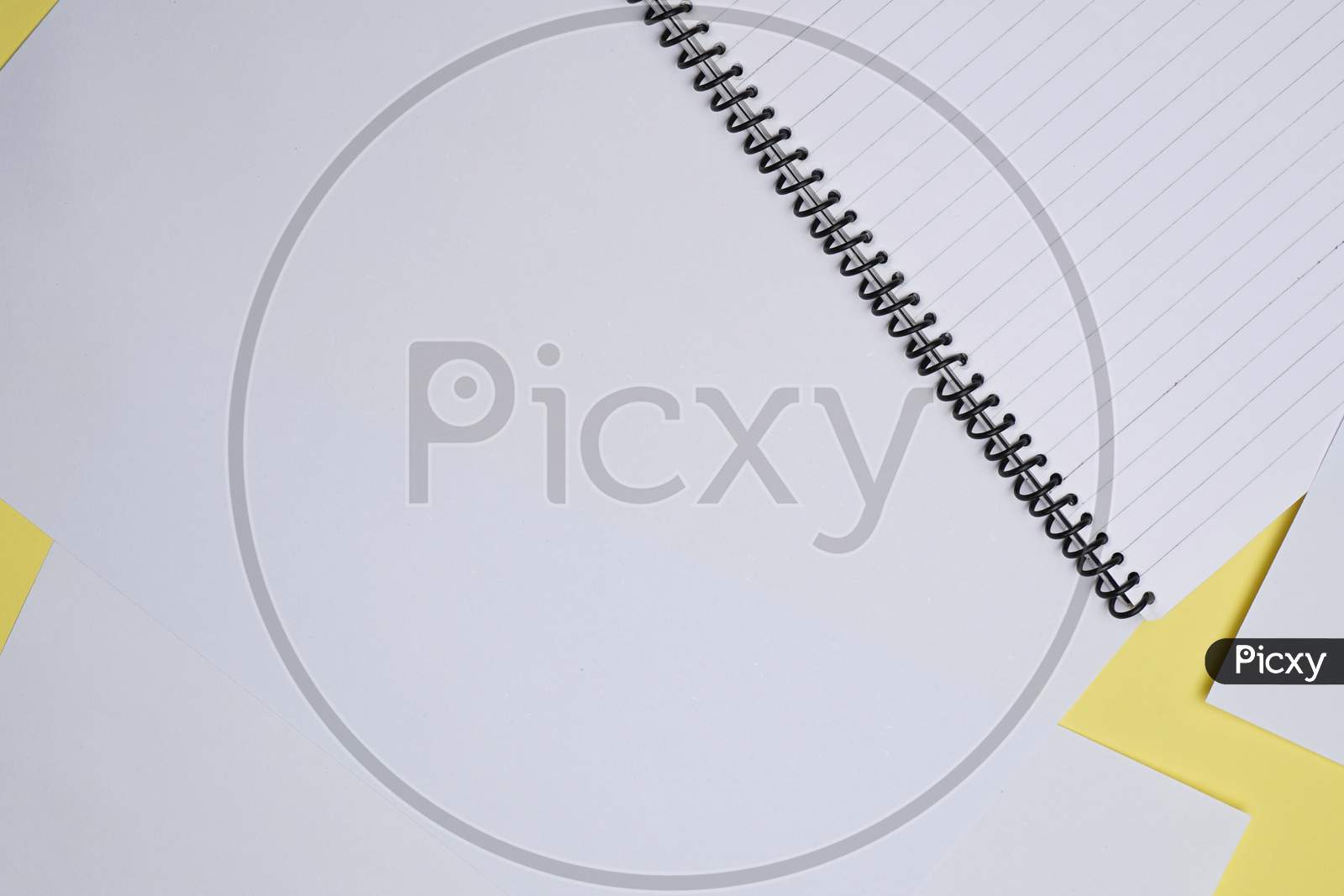 Creative Flay Lay, Table Top For Students, Office, Business Work.Spiral Notebook And White Sheet On A Yellow Background