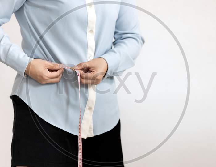 Close up,belly of female,asian young woman hold tape measure check waistline,healthy girl measuring around waist size with tape,waist measurement for fat checking,health care,weight control concept