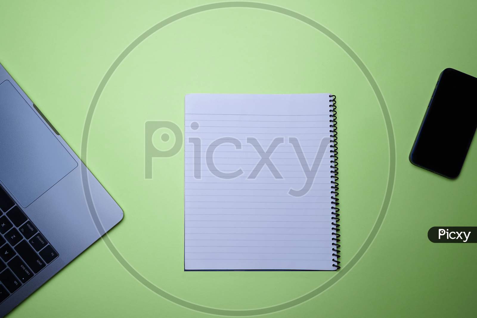 Business, Office, Student, Education Flat Lay, Table Top. Laptop, Spiral Notepad And Phone On Green Background