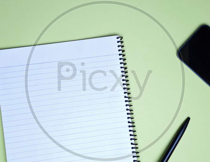Business, Office, Student, Education Flat Lay, Table Top. Spiral Notebook, Pen And Phone On Green Background