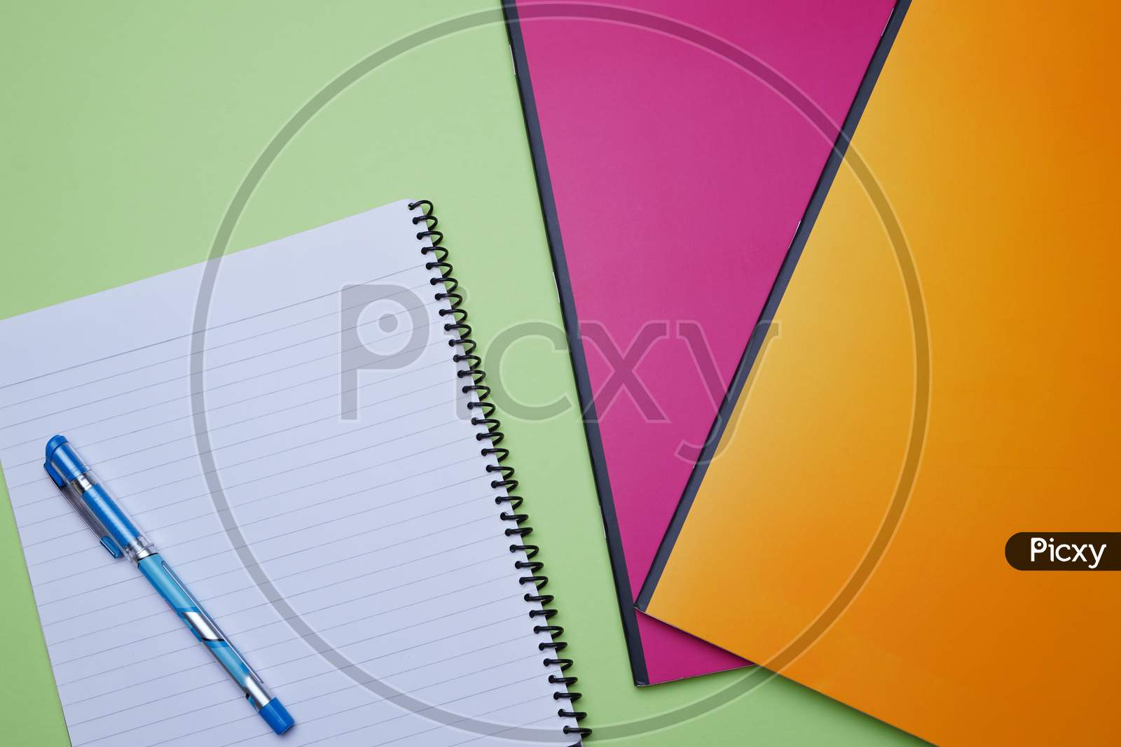 Business, Office, Student, Education Flat Lay, Table Top. Spiral Notebook, Pen, Colorful Notebook On Green Background