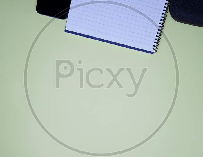Business, Office, Student, Education Flat Lay, Table Top. Speaker, Spiral Notebook, Phone And Pen On Green Background