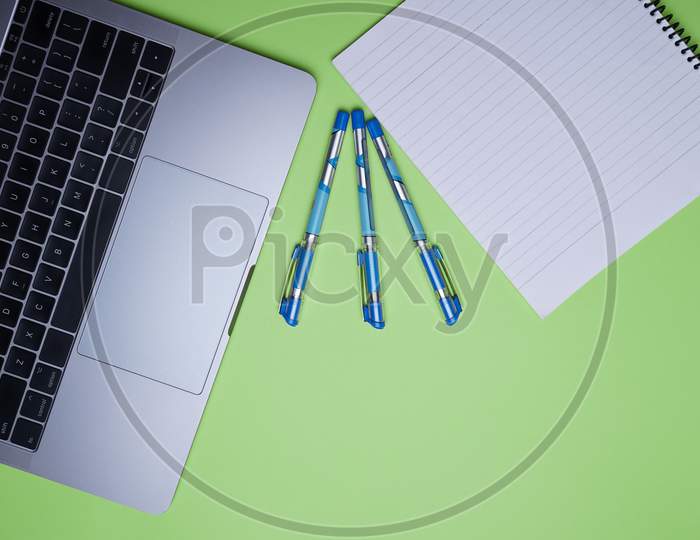 Creative Office, Business Professional Table Top, Flat Lay. Laptop, Pen And White Notebook On Green Background