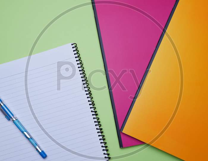 Business, Office, Student, Education Flat Lay, Table Top. Spiral Notebook, Pen, Colorful Notebook On Green Background